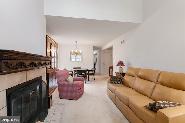 living area featuring light carpet, a tiled fireplace, visible vents, and an inviting chandelier