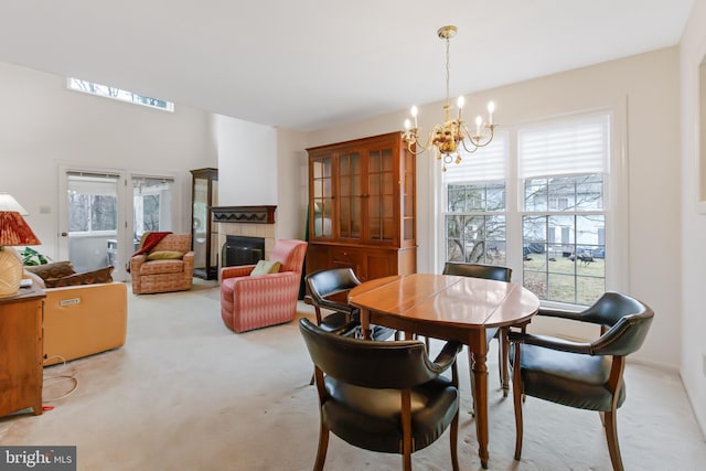 dining room with a chandelier, light colored carpet, and a tiled fireplace