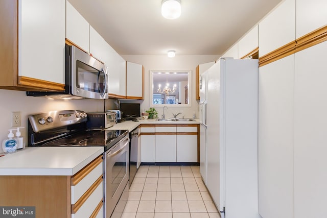 kitchen with light countertops, appliances with stainless steel finishes, light tile patterned flooring, and a sink