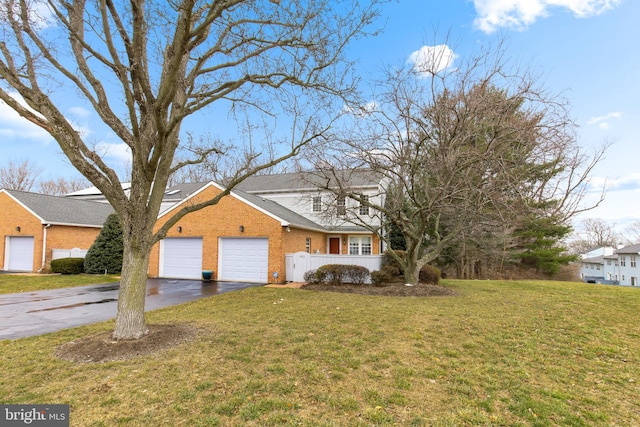 traditional-style home with aphalt driveway, brick siding, an attached garage, and a front lawn