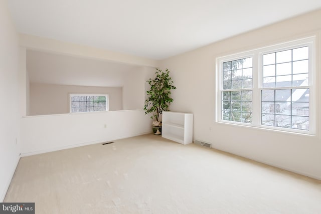 carpeted empty room featuring visible vents