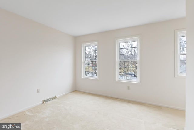 carpeted empty room featuring baseboards and visible vents