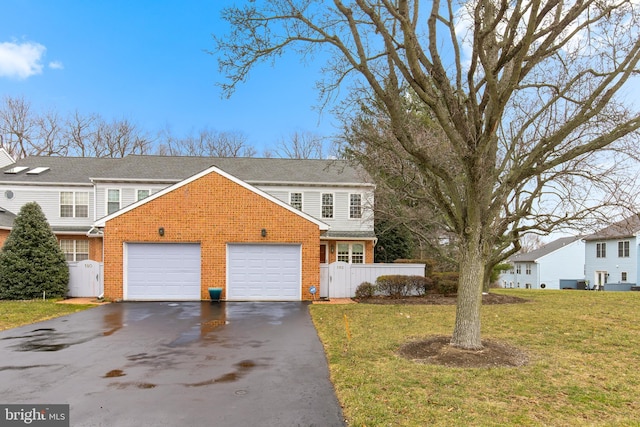 traditional home with a garage, brick siding, driveway, and a front lawn