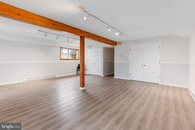 basement featuring light wood finished floors, baseboards, and a baseboard heating unit