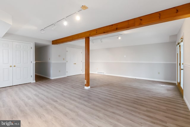 finished below grade area featuring light wood-style floors, baseboard heating, and baseboards