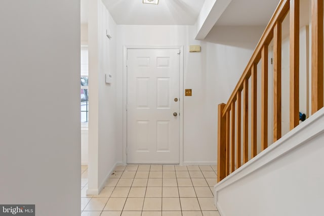 entryway with stairway, baseboards, and light tile patterned floors