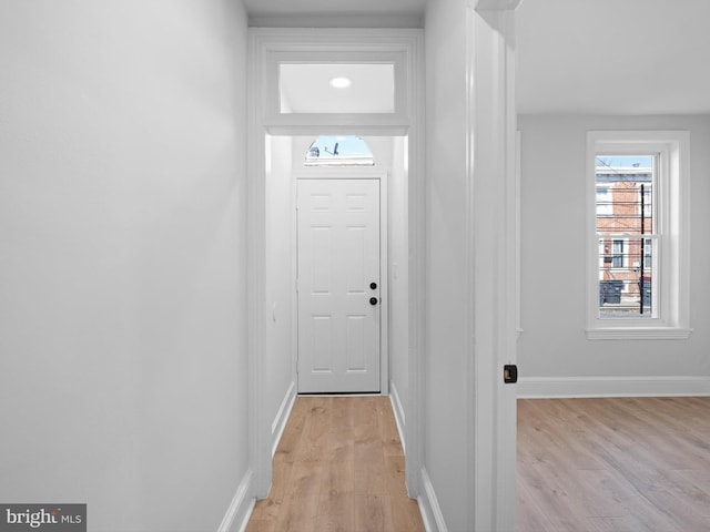 doorway to outside with light wood-type flooring and baseboards