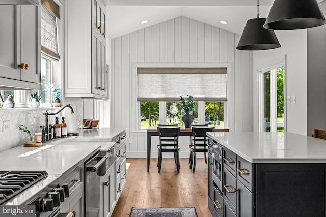 kitchen with light wood-type flooring, hanging light fixtures, a center island, vaulted ceiling, and tasteful backsplash