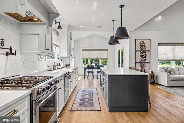 kitchen with white cabinets, stainless steel appliances, decorative light fixtures, and a center island