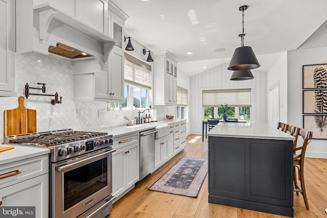 kitchen with appliances with stainless steel finishes, sink, pendant lighting, a kitchen island, and white cabinets