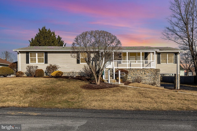 view of front of house with covered porch and a yard