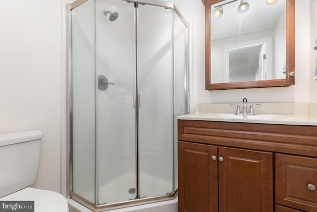 bathroom with vanity, a shower with door, and toilet