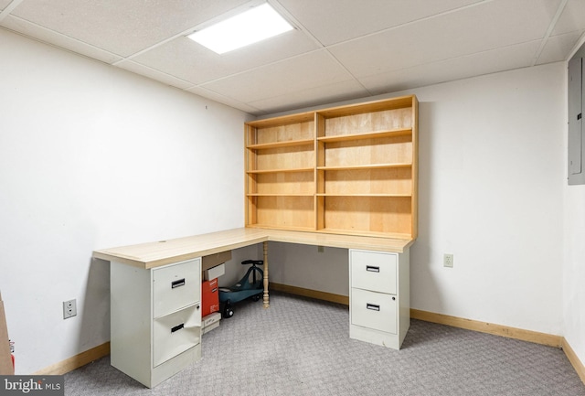 unfurnished office with a drop ceiling, built in desk, and light colored carpet