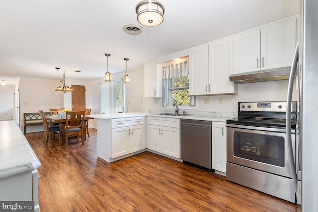 kitchen featuring kitchen peninsula, stainless steel appliances, sink, white cabinets, and pendant lighting