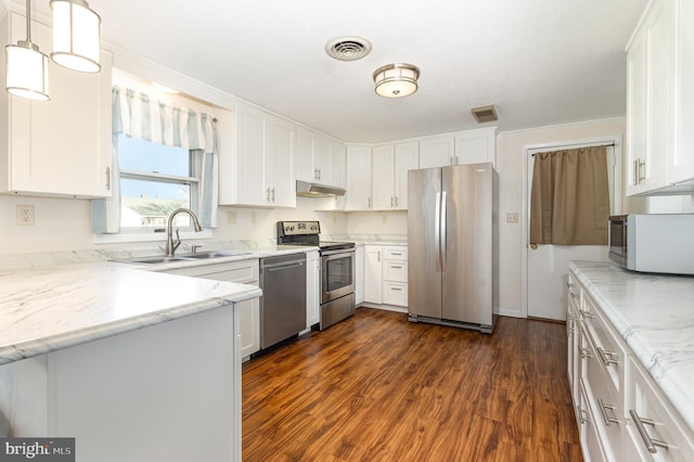 kitchen with white cabinets, stainless steel appliances, dark hardwood / wood-style floors, and decorative light fixtures