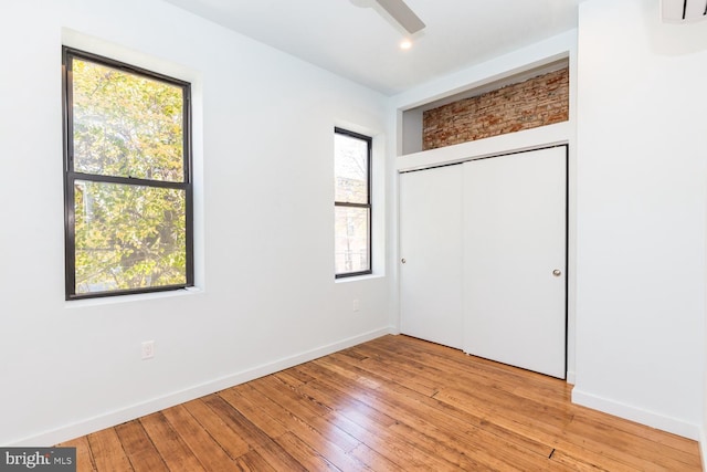 unfurnished bedroom featuring baseboards, a closet, a ceiling fan, and light wood-style floors