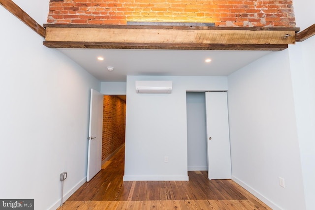 unfurnished bedroom featuring a wall unit AC, recessed lighting, wood finished floors, baseboards, and a closet