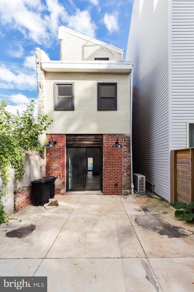 rear view of house featuring a patio, brick siding, concrete driveway, and fence