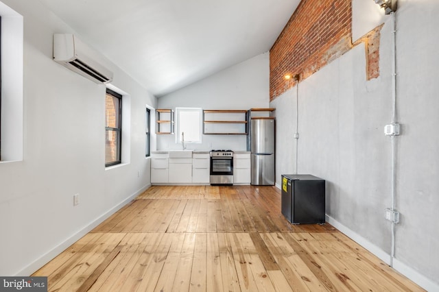 kitchen featuring light countertops, light wood-style flooring, appliances with stainless steel finishes, vaulted ceiling, and a wall mounted air conditioner