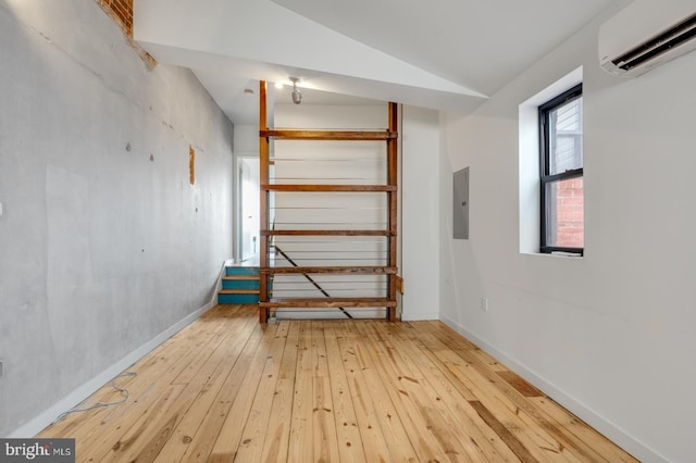 interior space featuring lofted ceiling, light wood-style floors, electric panel, and an AC wall unit