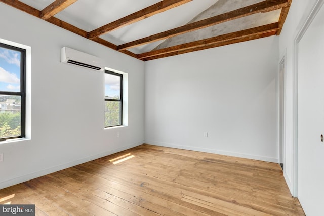 empty room with lofted ceiling with beams, a wall unit AC, baseboards, and light wood-style floors