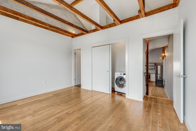 unfurnished bedroom featuring lofted ceiling with beams, wood finished floors, baseboards, a closet, and washer / clothes dryer