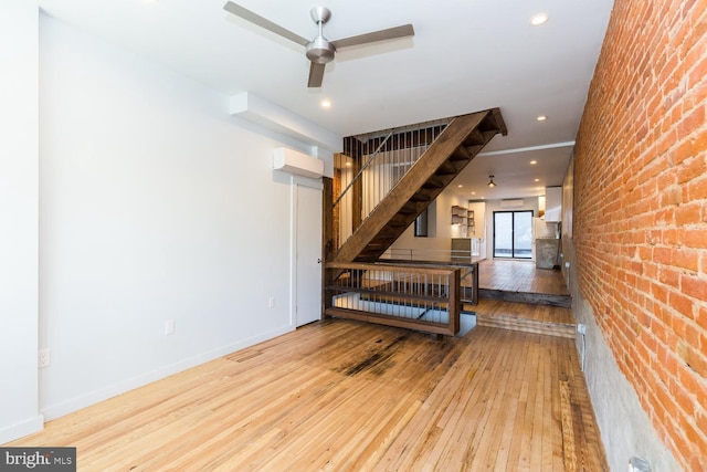 interior space with ceiling fan, recessed lighting, brick wall, wood finished floors, and baseboards