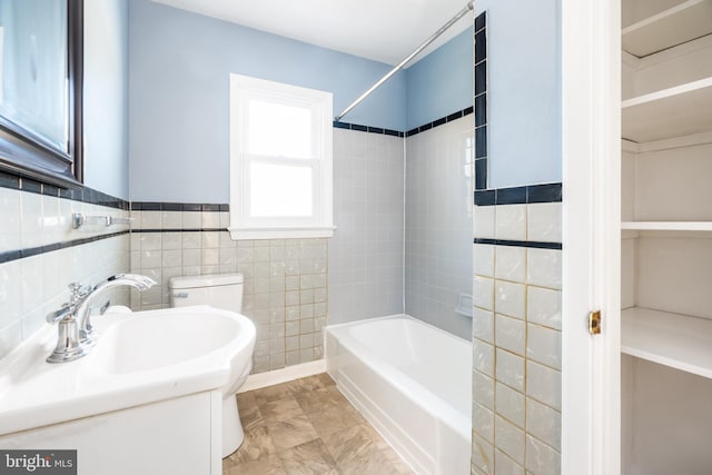 full bathroom featuring sink, tile walls, toilet, and tiled shower / bath