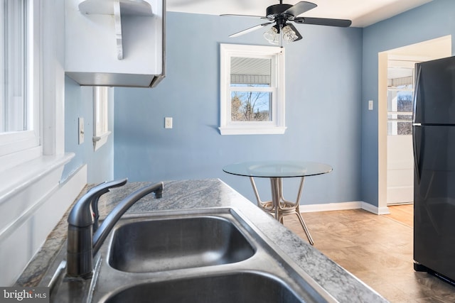 kitchen featuring a healthy amount of sunlight, sink, black refrigerator, and ceiling fan