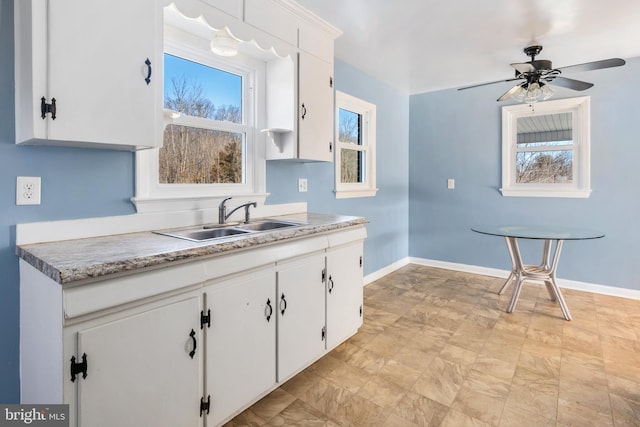 kitchen featuring ceiling fan, sink, and white cabinets