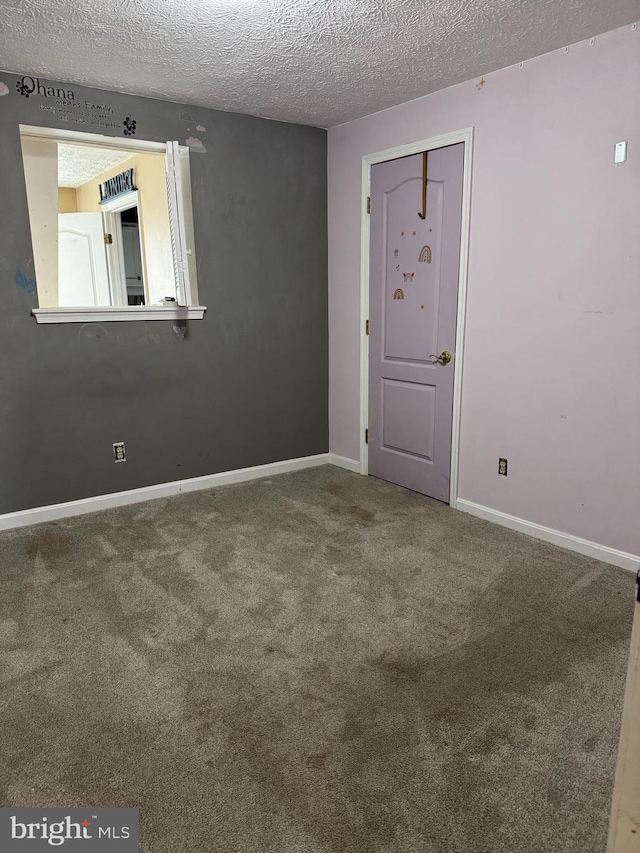 empty room featuring carpet, baseboards, and a textured ceiling