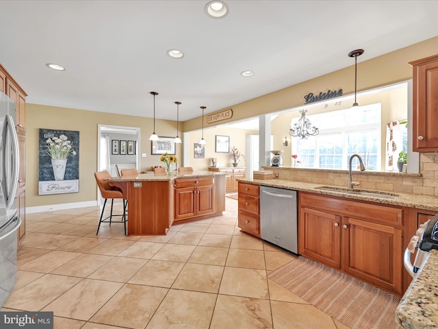 kitchen featuring tasteful backsplash, a breakfast bar area, appliances with stainless steel finishes, light stone countertops, and a sink