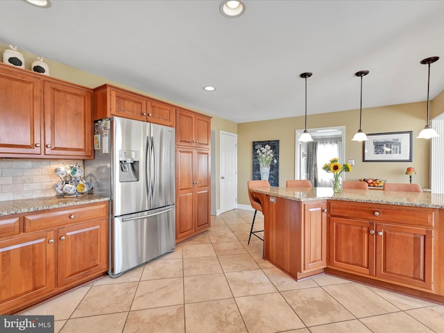 kitchen featuring light tile patterned flooring, brown cabinets, backsplash, and stainless steel fridge with ice dispenser