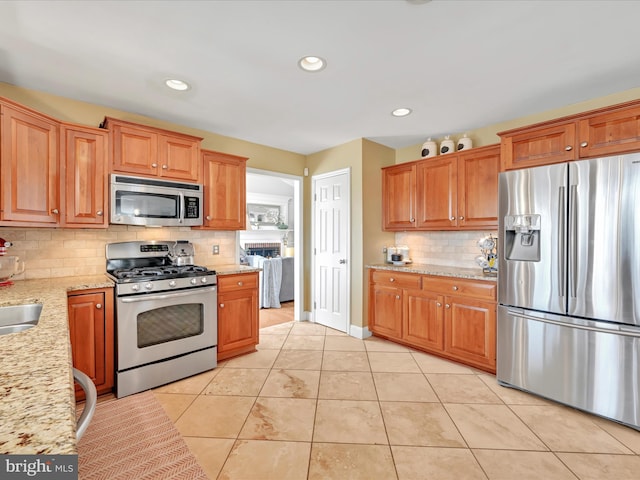 kitchen with light stone counters, light tile patterned floors, recessed lighting, backsplash, and appliances with stainless steel finishes