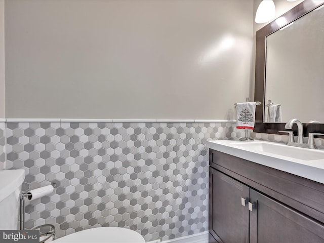 bathroom featuring a wainscoted wall, vanity, toilet, and tile walls