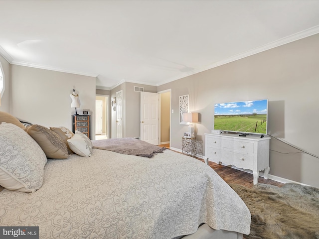 bedroom featuring ornamental molding, visible vents, baseboards, and wood finished floors