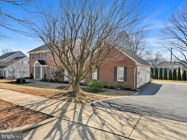 view of front of property featuring a garage, brick siding, and driveway