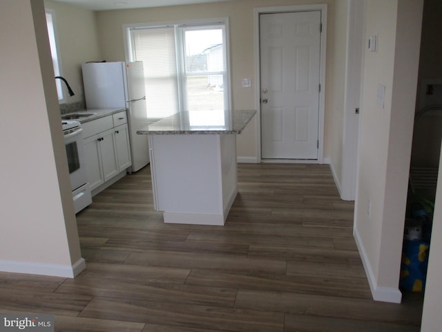 kitchen with a center island, sink, white appliances, light stone counters, and white cabinets