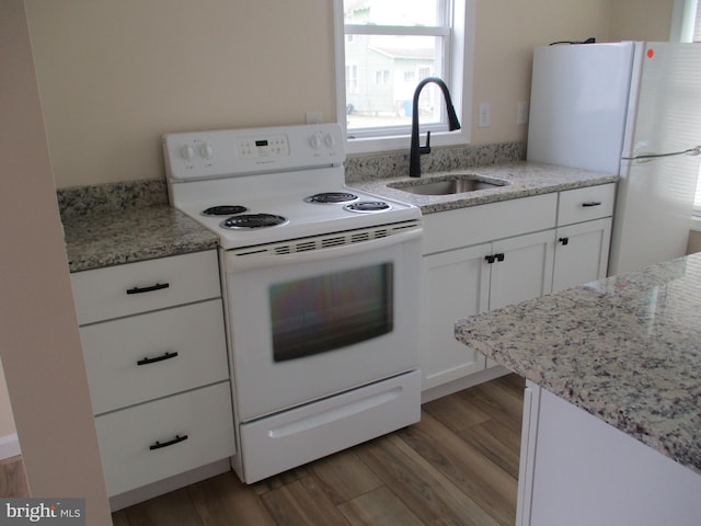 kitchen with white cabinetry, light stone countertops, light hardwood / wood-style floors, sink, and white appliances