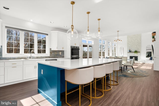 kitchen featuring white cabinets, a center island, dark wood-type flooring, and decorative light fixtures