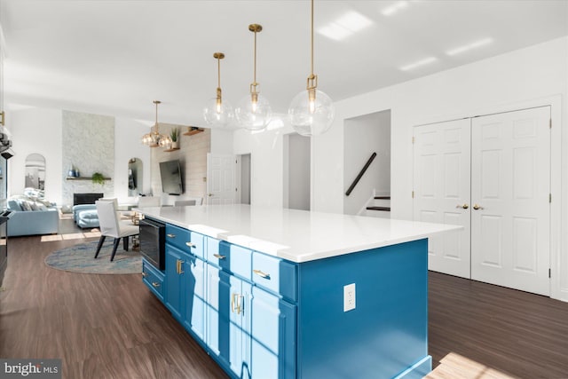 kitchen with blue cabinetry, dark wood-type flooring, a kitchen island, and decorative light fixtures