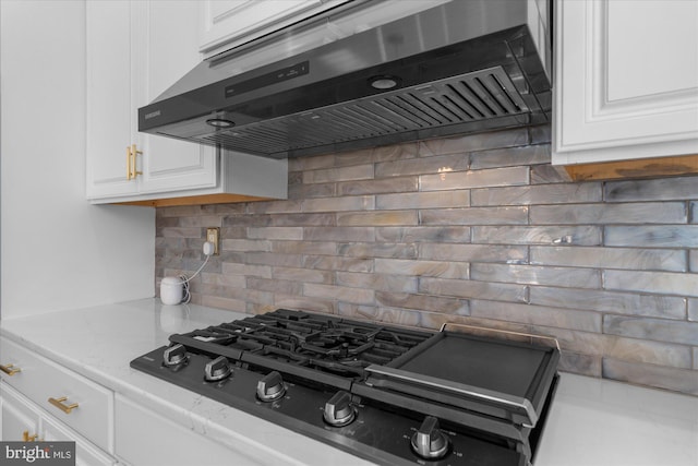 kitchen with gas stovetop, white cabinetry, backsplash, and range hood