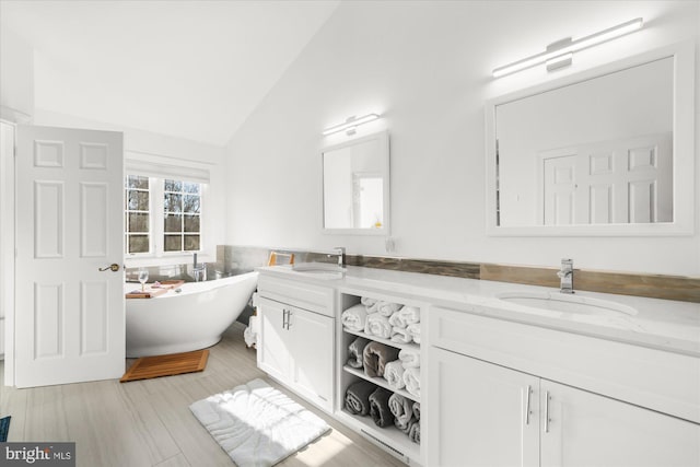 bathroom featuring a washtub, lofted ceiling, tile walls, and vanity