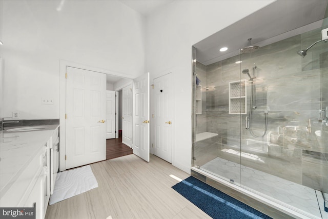 bathroom featuring hardwood / wood-style flooring, sink, an enclosed shower, and a towering ceiling