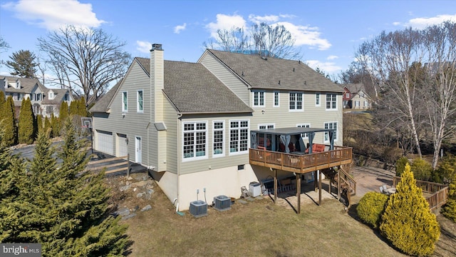 back of property featuring central AC, a deck, a garage, and a yard