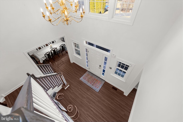 entrance foyer with dark hardwood / wood-style flooring, a high ceiling, and a notable chandelier