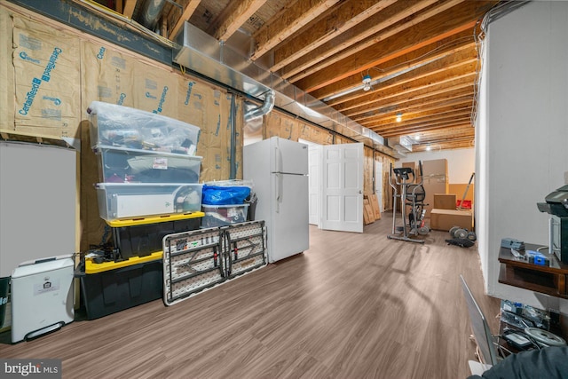 basement with wood-type flooring and white refrigerator