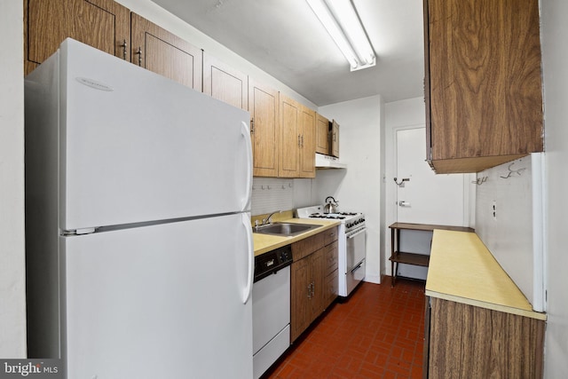 kitchen with light countertops, white appliances, a sink, and under cabinet range hood