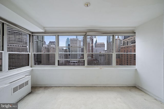 unfurnished sunroom with radiator, plenty of natural light, and a city view