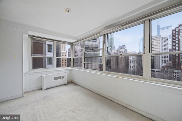 unfurnished sunroom with a view of city and radiator heating unit